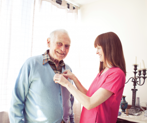 Care giving nurse providing Personal Home Care Services to elderly man in his own home helping him to age in place