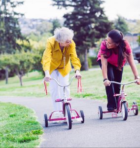 An elderly lady having fun riding a scooter for transportation with her nurse next door care giver