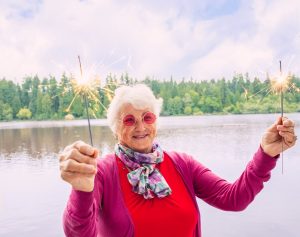 elderly lady holding sparklers celebrating HappierAgeing with Nurse Next Door home care 