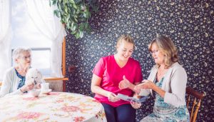 elderly lady, care giving daughter and caregiver looking at home care brochure