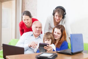 Grandfather and grandchildren uses few various technology devices at home interior