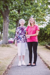 nurse holding hands with elderly woman