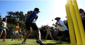 a family of several generations plays backyard cricket