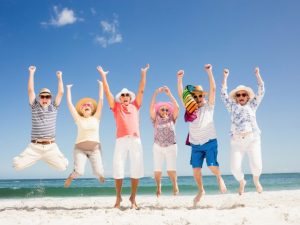 6 older people jumping on the beach, celebrating life